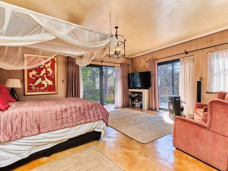 Spacious bedroom featuring polished concrete floors, a built-in media console, and dual sliding glass doors providing access to the outdoor area.