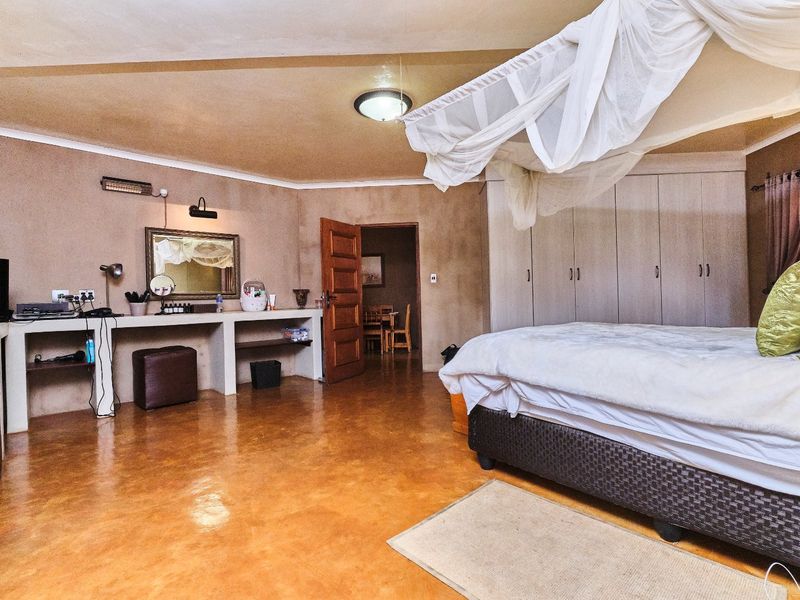 Spacious bedroom featuring built-in cupboards, a concrete vanity area, and polished concrete flooring, offering a rustic aesthetic with ample storage space.