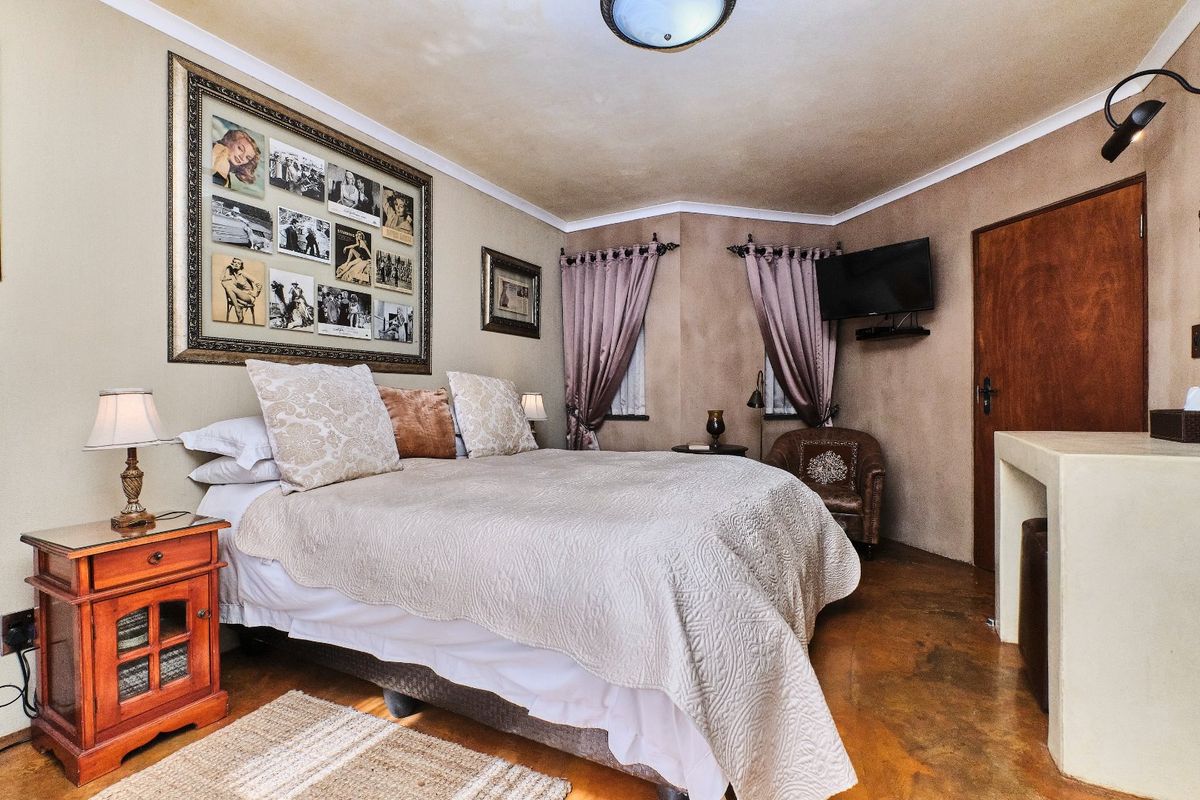 A bedroom featuring concrete flooring, coving, and a timber door, offering a rustic aesthetic with potential for modern updates.