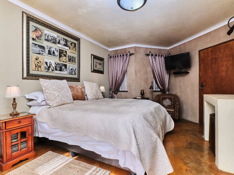 A bedroom featuring concrete flooring, coving, and a timber door, offering a rustic aesthetic with potential for modern updates.