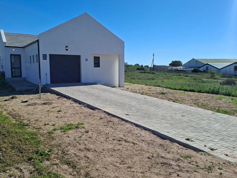 Front view of a modern residential property featuring a paved driveway, single garage, and clean white exterior finish.