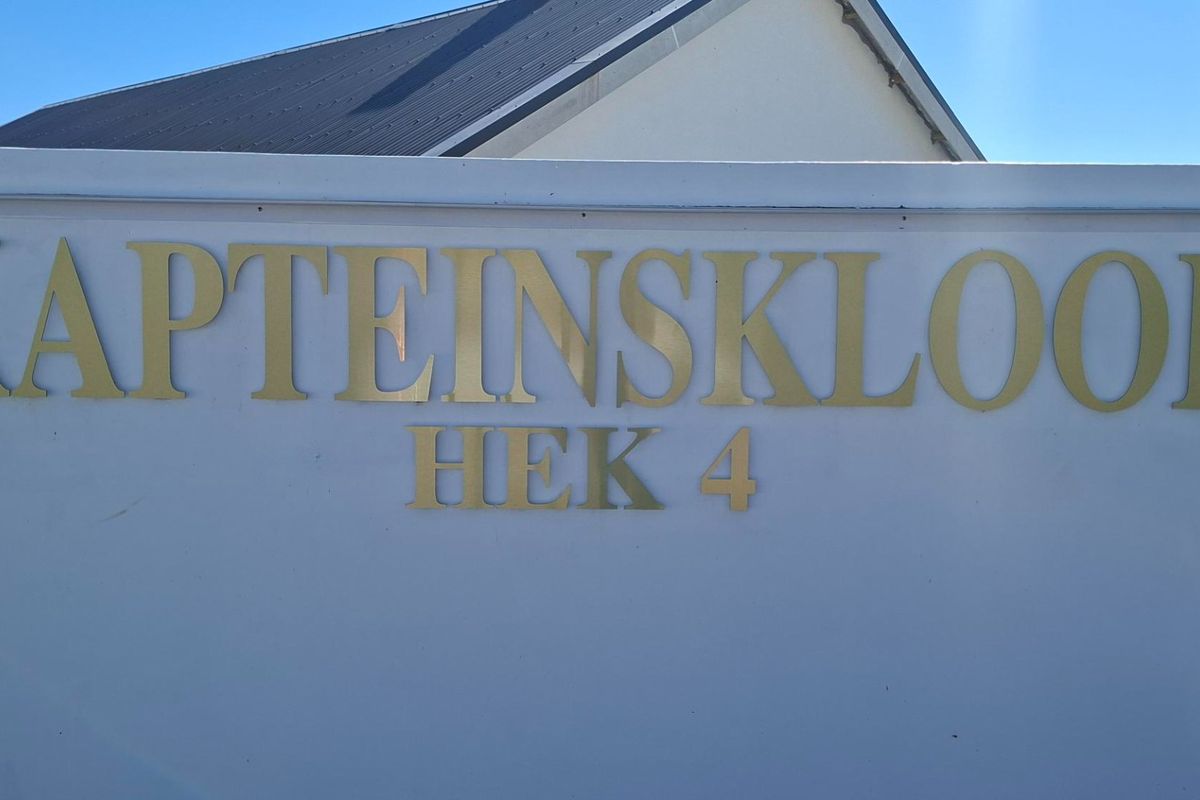 A clear view of the property boundary wall featuring metal signage for Kapteinskloof Hek 4.