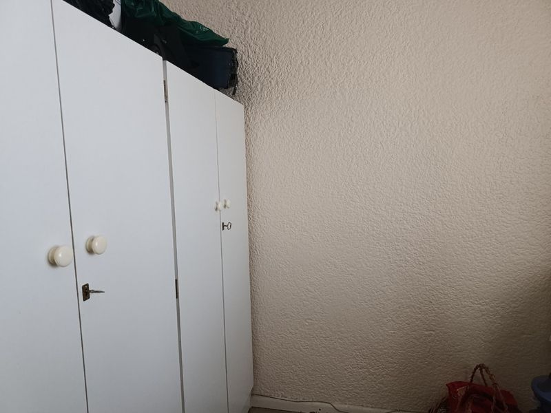 A bedroom featuring a white built-in wardrobe with textured wall finishes.