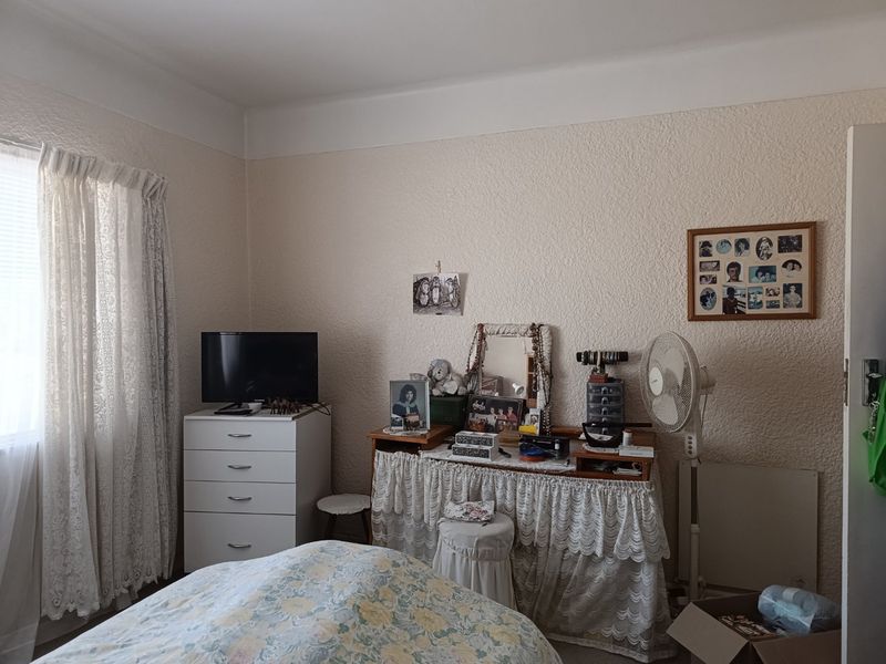 A bedroom featuring textured walls and a window with curtains, providing a functional living space.