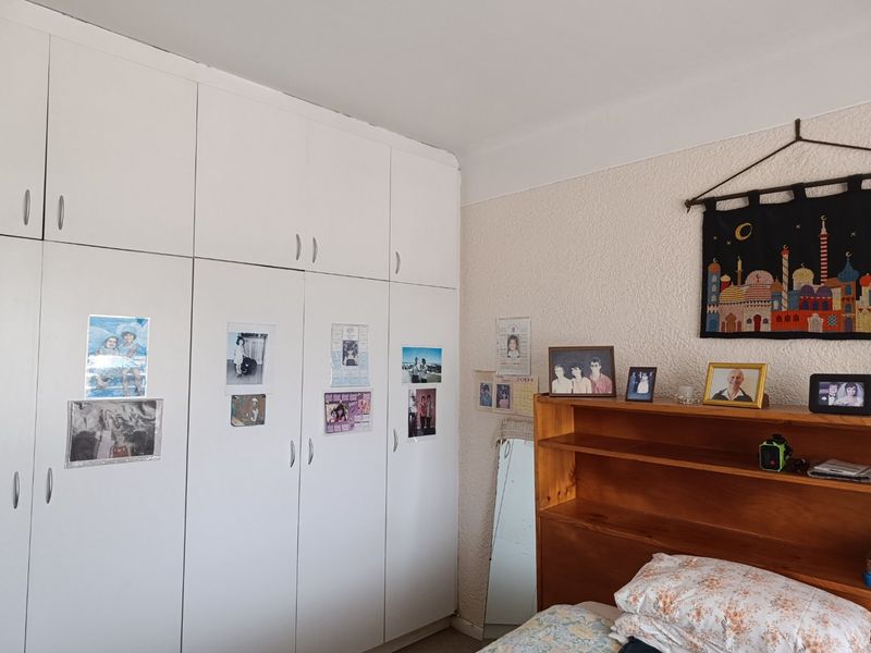 Bedroom featuring floor-to-ceiling white built-in cupboards and textured wall finishes, offering ample storage space.