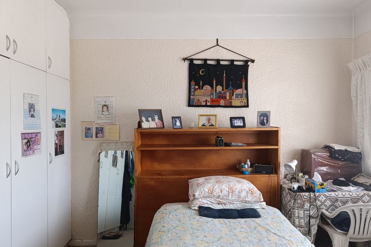 A bedroom featuring white built-in cupboards and textured wall finishes, providing functional storage space.