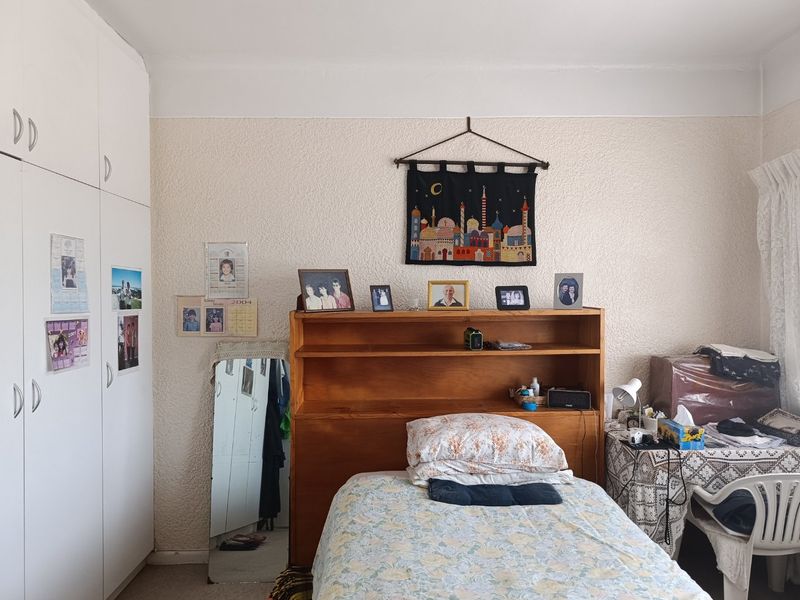 A bedroom featuring white built-in cupboards and textured wall finishes, providing functional storage space.