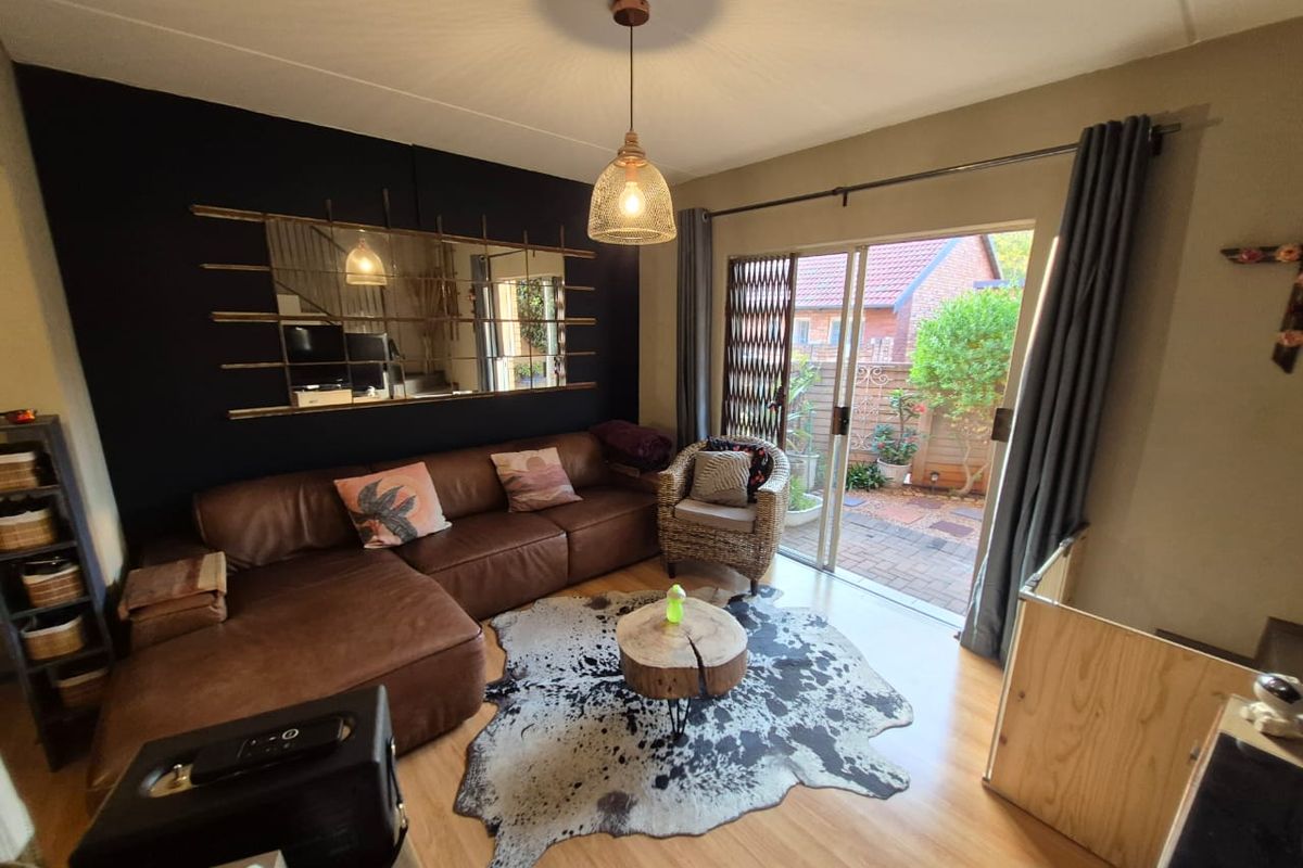 A cozy living room featuring laminate flooring and a sliding glass door that provides direct access to a paved outdoor patio area.