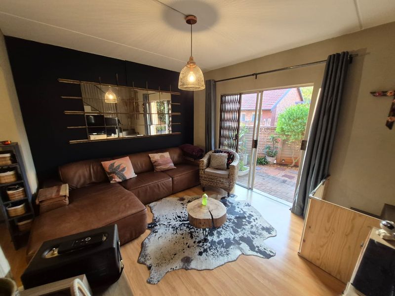 A cozy living room featuring laminate flooring and a sliding glass door that provides direct access to a paved outdoor patio area.