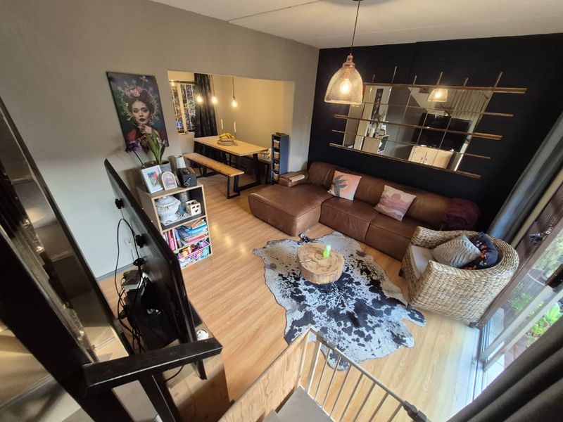 Open plan living and dining area featuring laminate flooring, modern pendant lighting, and direct access to an outdoor space via sliding glass doors.
