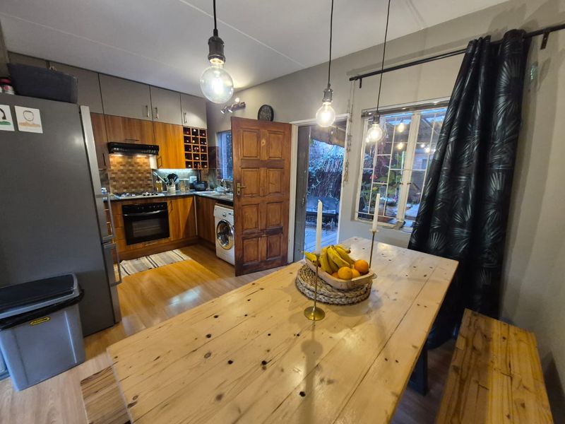 Open-plan kitchen and dining area featuring wood-finish cabinetry, built-in appliances, and direct access to an outdoor patio space.