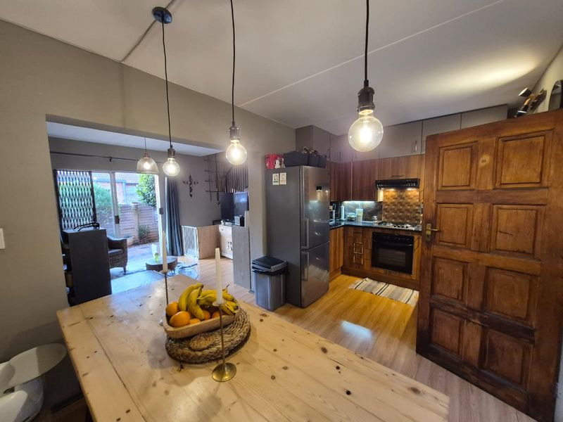 Open-plan kitchen and living area featuring wooden cabinetry, built-in oven, laminate flooring, and direct access to a rear patio through sliding glass doors.