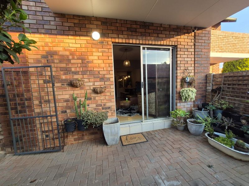 A covered brick-walled patio area featuring paved flooring and a sliding glass door providing access to the interior living space.