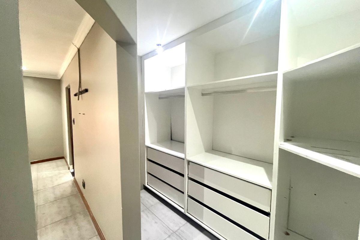A clean, empty bedroom featuring modern built-in cabinetry with ample storage space and neutral tiled flooring.
