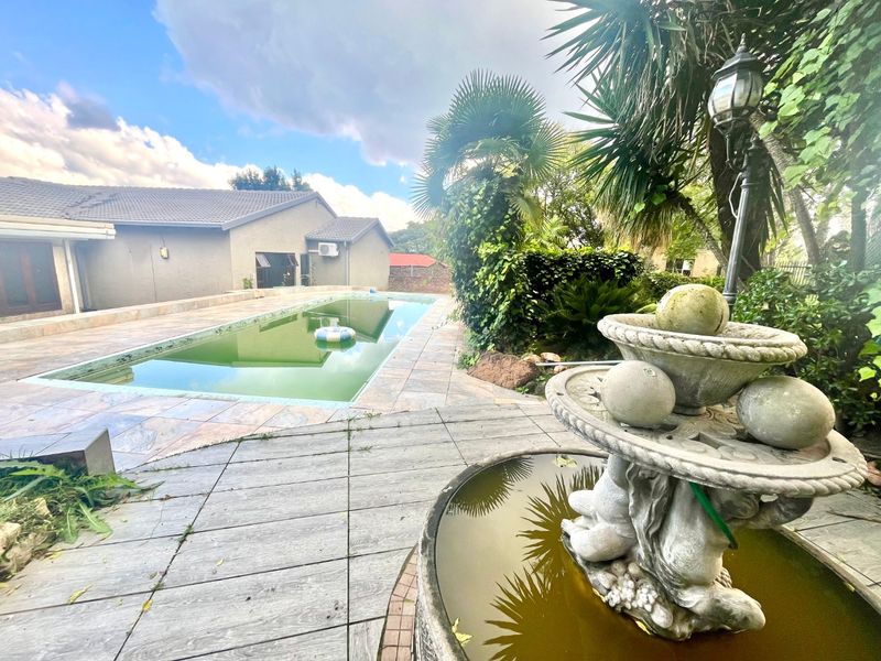 Outdoor pool area featuring a tiled patio, a stone fountain, and a swimming pool requiring maintenance.