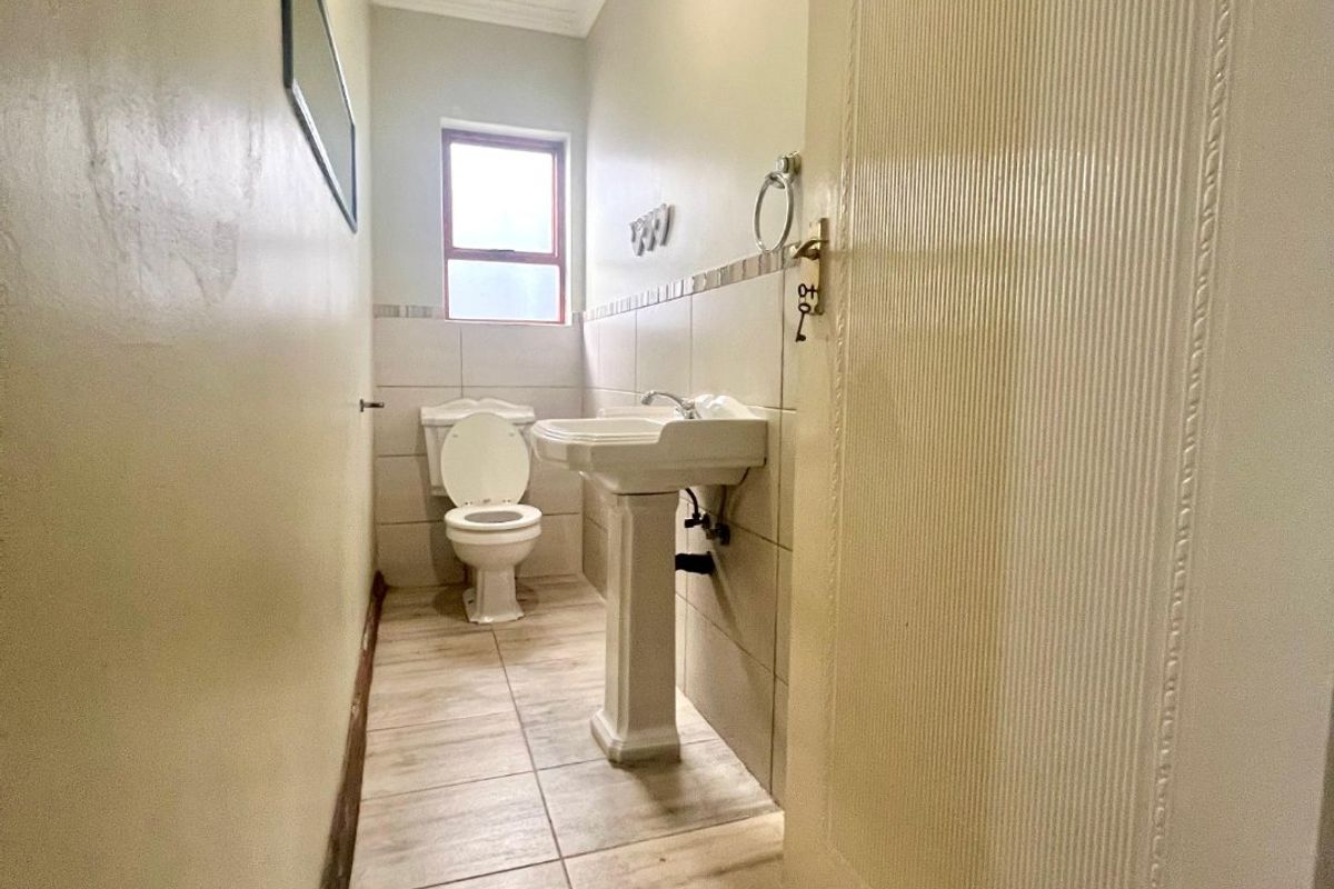 A compact guest bathroom featuring a pedestal basin, toilet, and neutral tiled finishes.