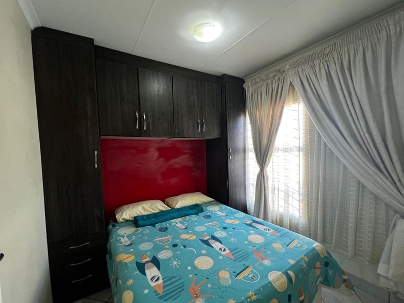 A bedroom featuring dark wood built-in cupboards with integrated storage and a window with curtain rails.