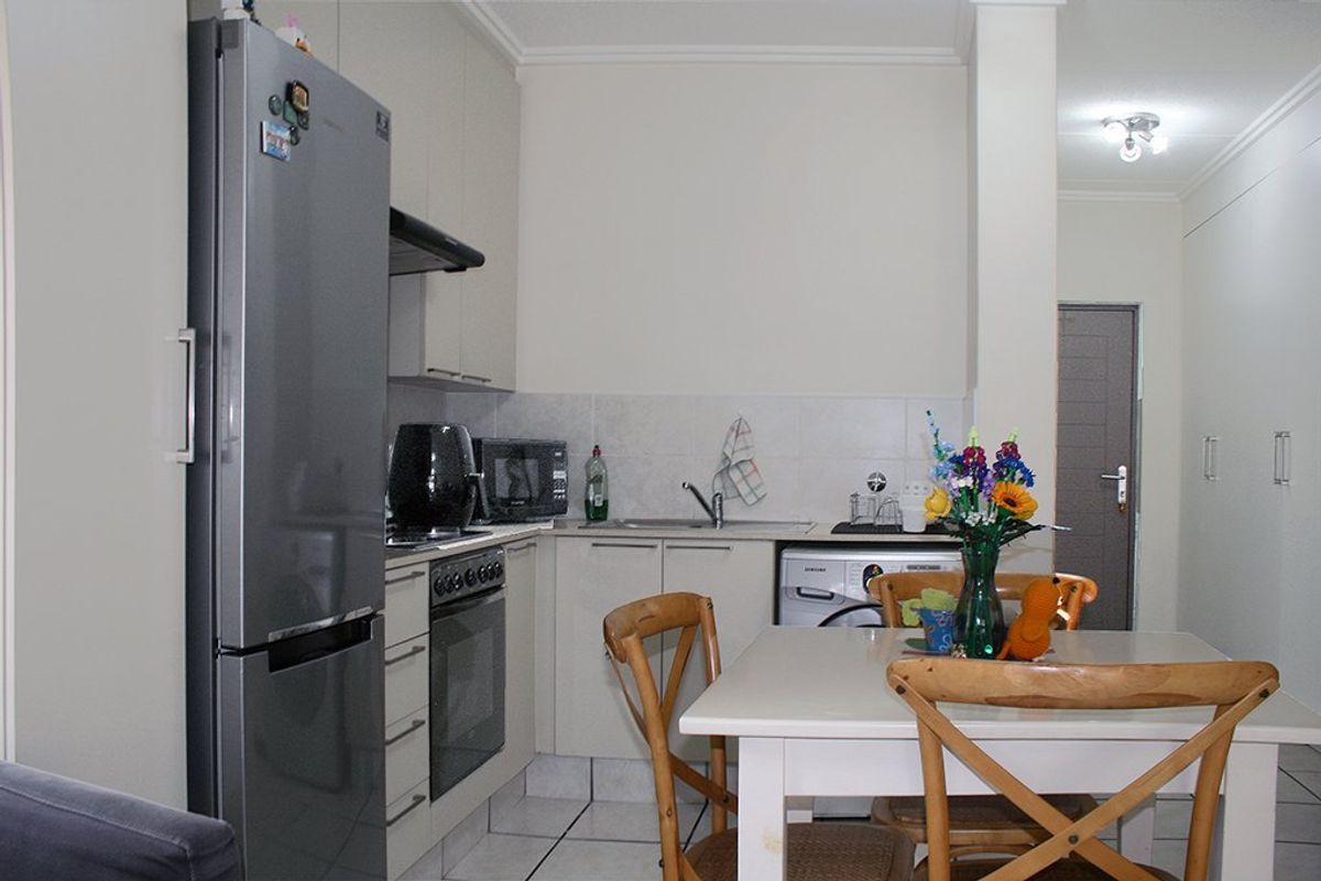 Compact kitchen featuring built-in cabinetry, tiled backsplash, integrated oven with extractor fan, and tiled flooring, seamlessly connected to the dining area.