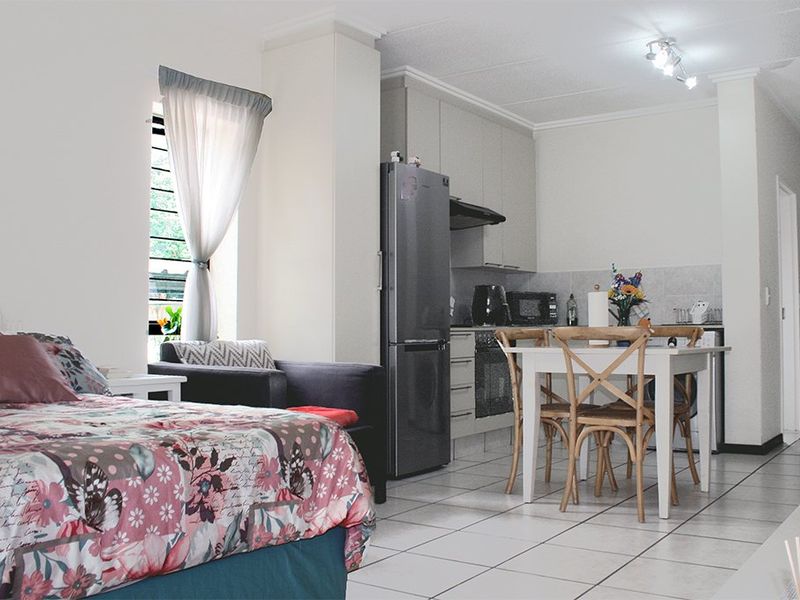 Open-plan studio apartment featuring a compact kitchen with built-in cabinetry, oven, and hob, seamlessly integrated with the living and sleeping area.