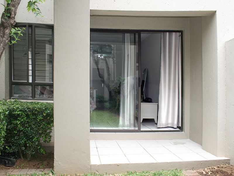 A covered patio area featuring tiled flooring and a sliding glass door providing access to the interior living space.
