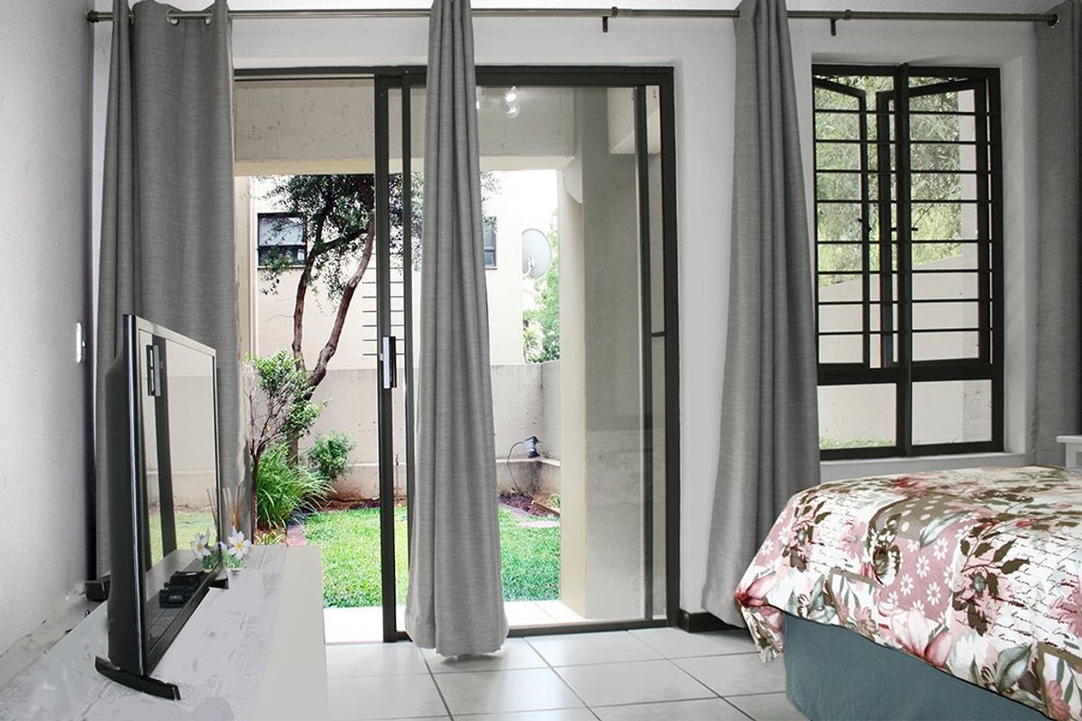Bedroom featuring tiled flooring and a sliding glass door providing direct access to a private garden area.