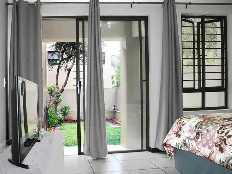 Bedroom featuring tiled flooring and a sliding glass door providing direct access to a private garden area.