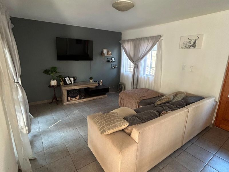 A living room featuring tiled flooring and a dark grey accent wall, providing a functional space for relaxation.