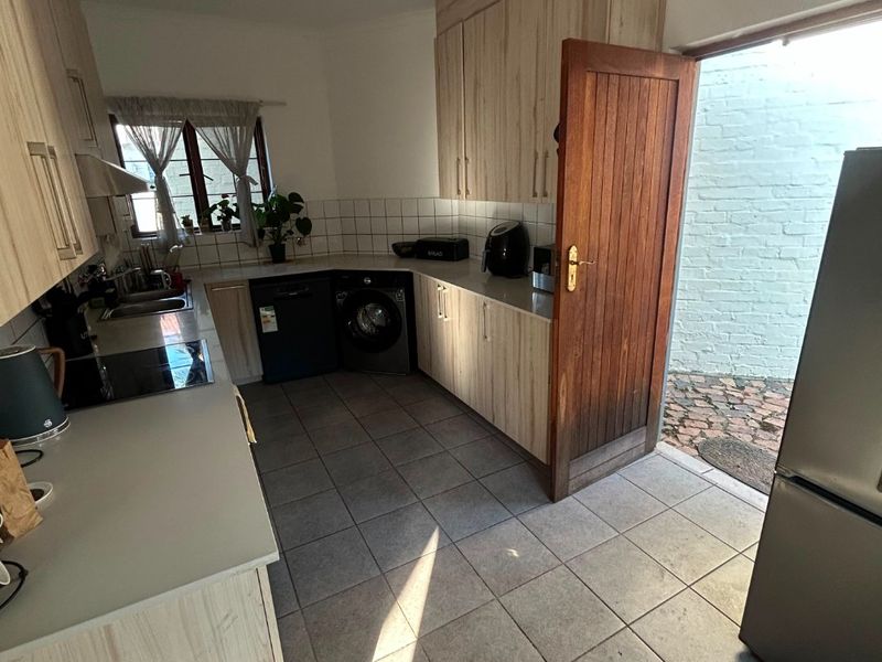 Functional kitchen featuring light wood-look cabinetry, tiled flooring, and direct access to an outdoor courtyard area.
