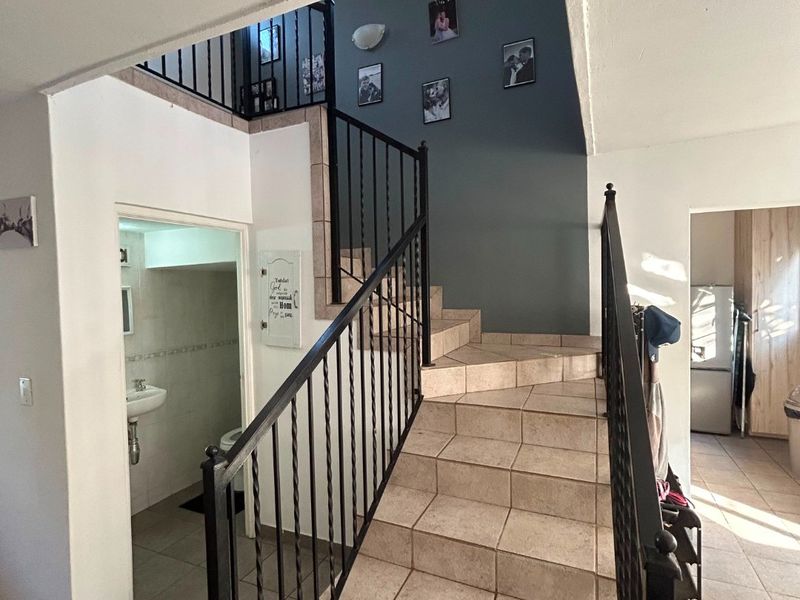Entrance area featuring a tiled staircase with wrought iron balustrade and access to a ground floor guest bathroom.