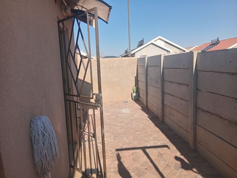 A private rear courtyard featuring paved flooring, enclosed by precast concrete boundary walls and secured with a metal gate.