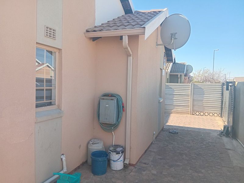 A side view of the property showing the exterior wall, roof tiling, guttering, satellite dish, and paved driveway area.