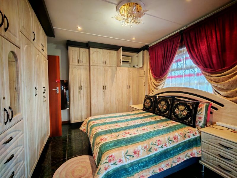 A bedroom featuring extensive built-in wooden cabinetry, tiled flooring, and a decorative ceiling light fixture.