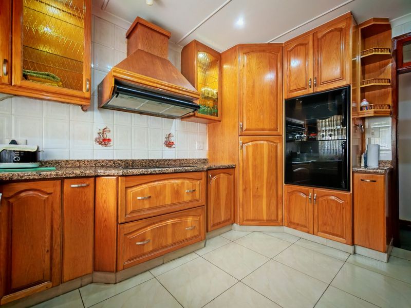 A functional kitchen featuring traditional wooden cabinetry, granite countertops, a built-in oven, and an extractor fan with tiled flooring and backsplash.