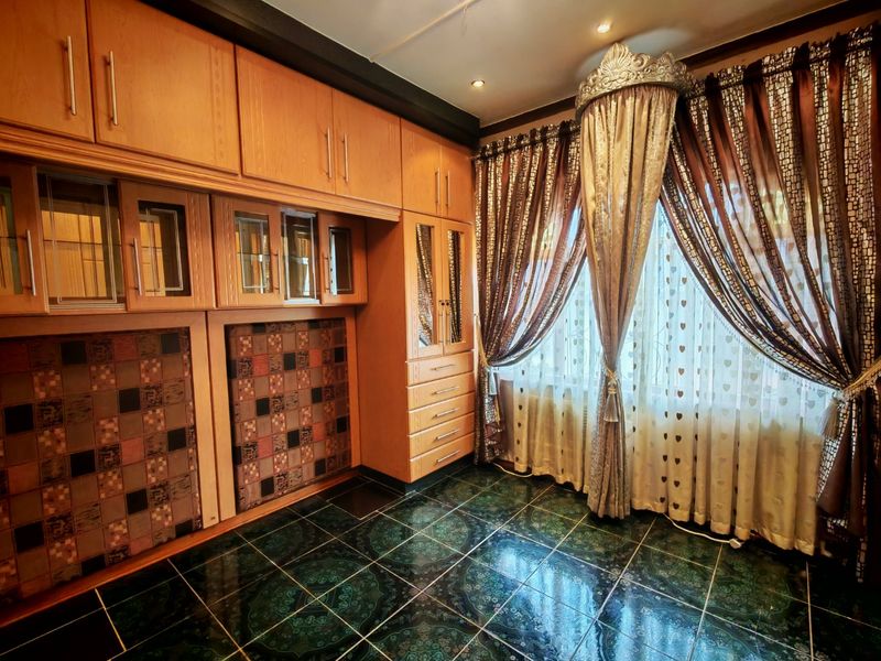 A bedroom featuring extensive built-in wooden cabinetry, dark patterned tiled flooring, and recessed ceiling lighting.