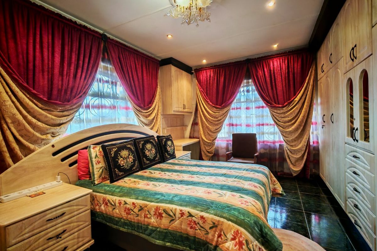 A bedroom featuring built-in wooden cupboards, tiled flooring, and recessed lighting, offering a functional space with traditional design elements.