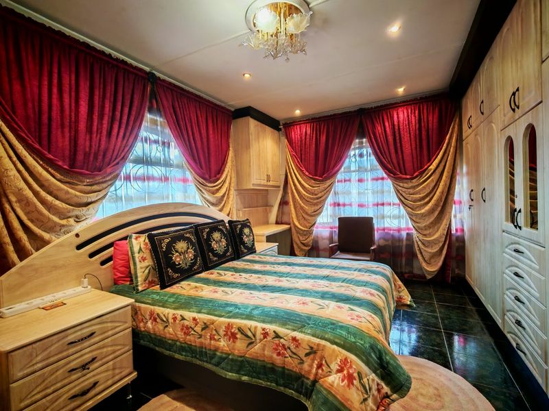 A bedroom featuring built-in wooden cupboards, tiled flooring, and recessed lighting, offering a functional space with traditional design elements.