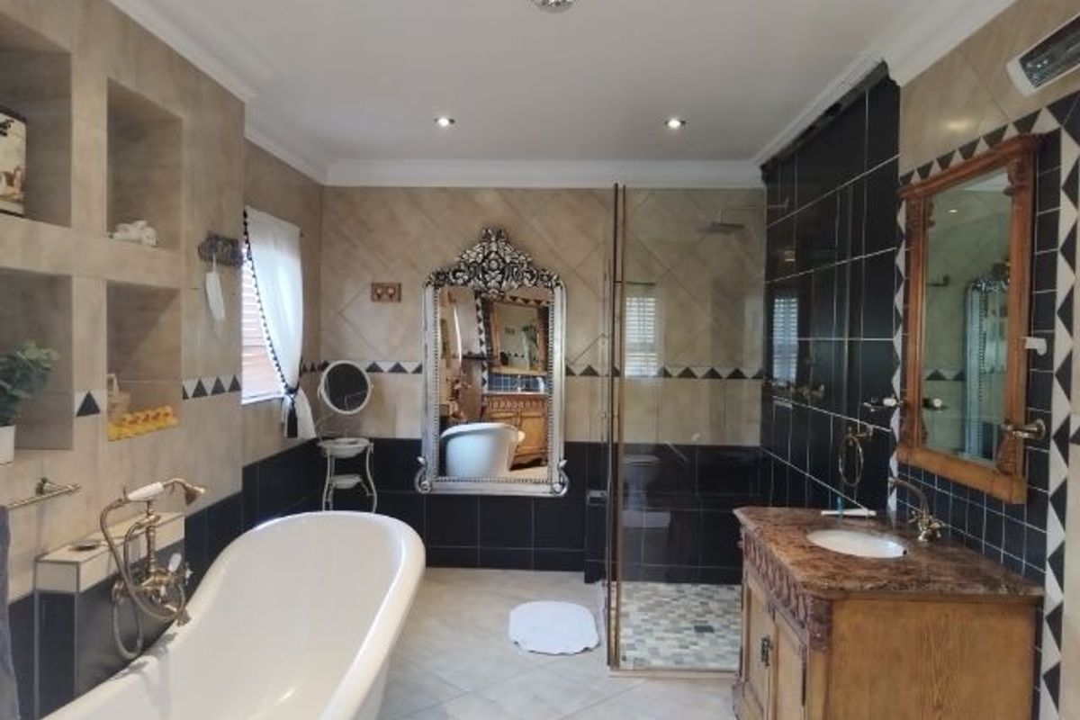 Spacious bathroom featuring a freestanding bathtub, a separate walk-in shower, and a vanity with a stone countertop and integrated sink.