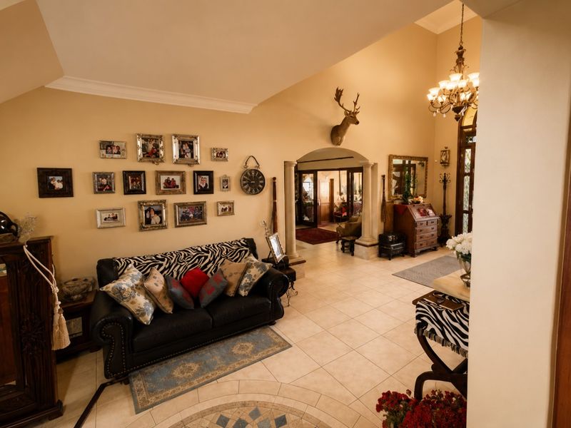 Spacious living area featuring tiled flooring, decorative columns, and an elegant archway leading to adjacent rooms, complemented by a classic chandelier.