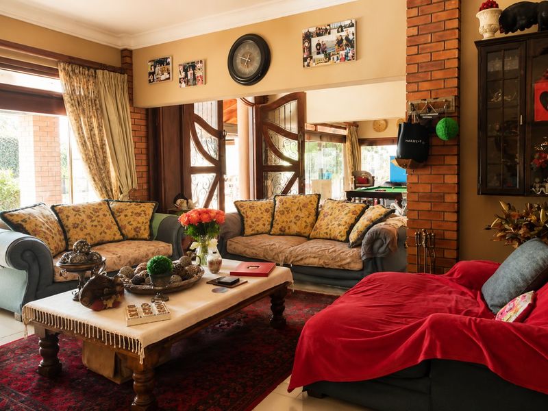A spacious living room featuring exposed brick architectural elements, tiled flooring, and large timber-framed glass doors providing access to the outdoor area.