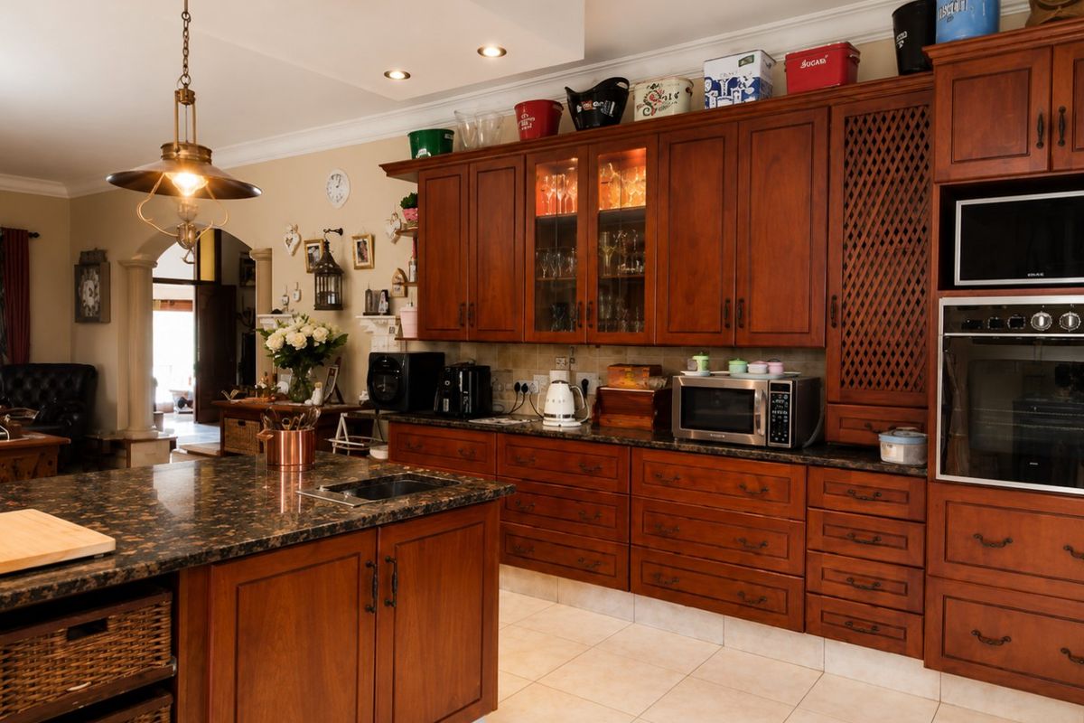 A spacious kitchen featuring rich wooden cabinetry, granite countertops, a central island, and integrated appliances, offering a warm and functional culinary space.