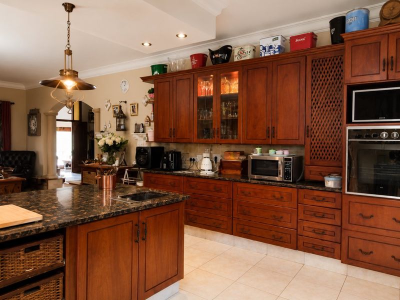 A spacious kitchen featuring rich wooden cabinetry, granite countertops, a central island, and integrated appliances, offering a warm and functional culinary space.