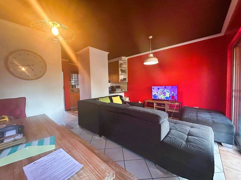 Open-plan living area featuring tiled flooring, pendant lighting, and a sliding glass door leading to the exterior, with a bold red accent wall.