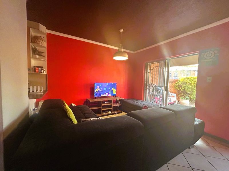 Living room featuring tiled flooring, built-in shelving, and a sliding glass door with security gate providing access to the exterior.