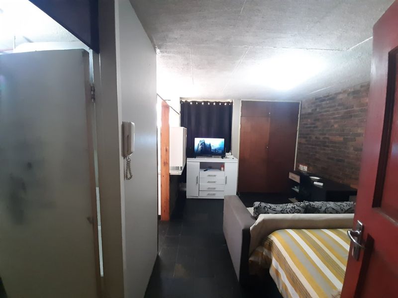 A bedroom featuring an exposed brick feature wall, built-in wardrobe storage, and an intercom system, requiring cosmetic updates to improve the overall finish.