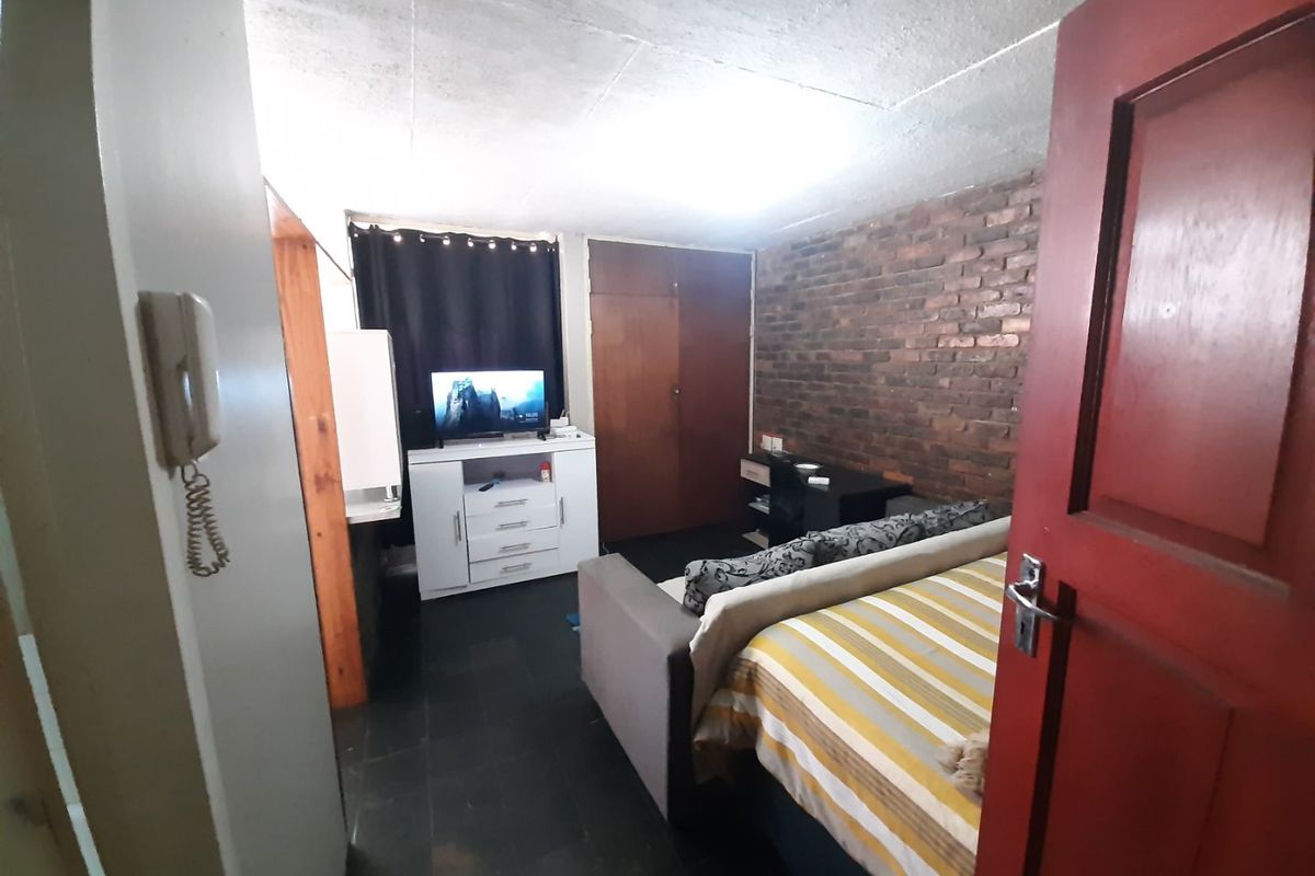 Bedroom featuring an exposed brick feature wall, built-in cupboard storage, and an intercom system.