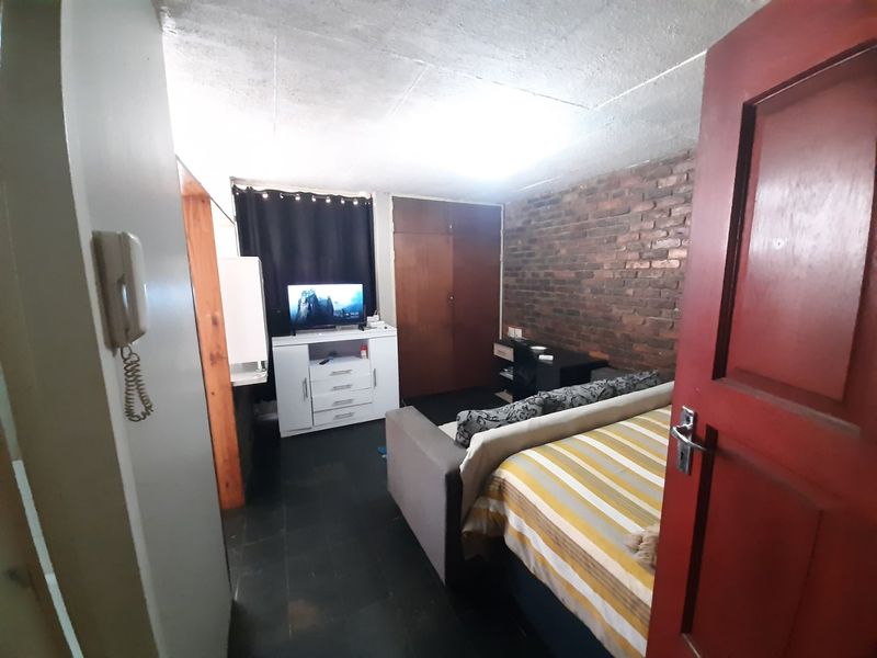 Bedroom featuring an exposed brick feature wall, built-in cupboard storage, and an intercom system.
