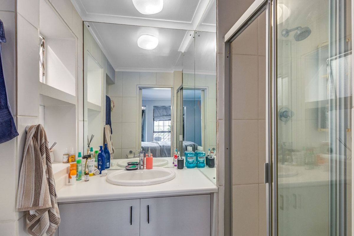 A functional bathroom featuring a vanity with a drop-in sink, a large wall mirror, and a separate shower enclosure with tiled walls.