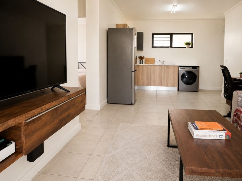 Open-plan living area featuring tiled flooring and a functional kitchen space with integrated laundry facilities.