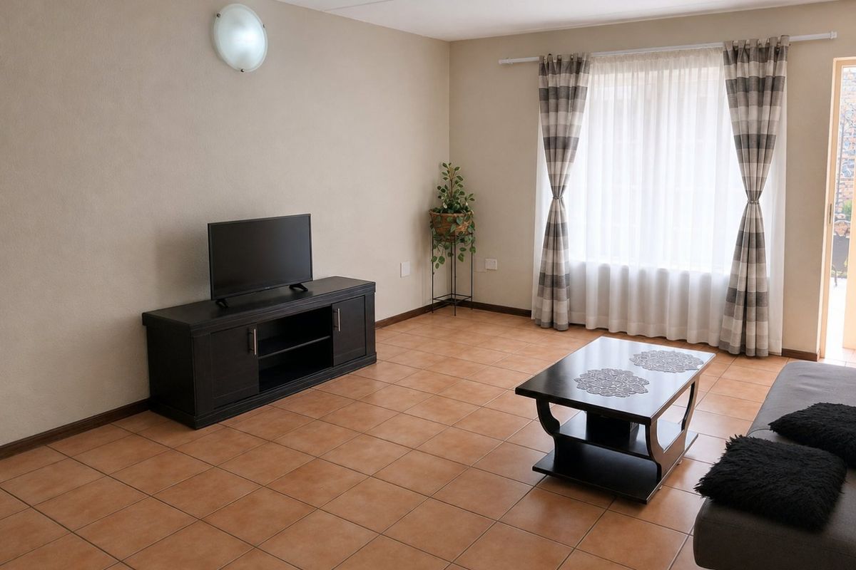 A spacious living room featuring neutral wall tones and durable ceramic tile flooring, offering a clean and functional layout with natural light.
