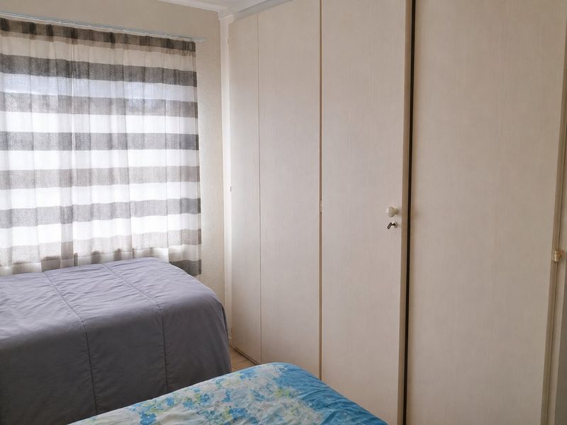 A functional bedroom featuring ample built-in cupboard storage and natural light from the window.